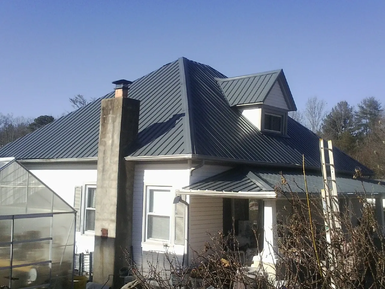 Dark blue standing seam metal roof on a white farmhouse with dormer — Slate & Tile Roof Repair by Roofing Brothers in San Gregorio