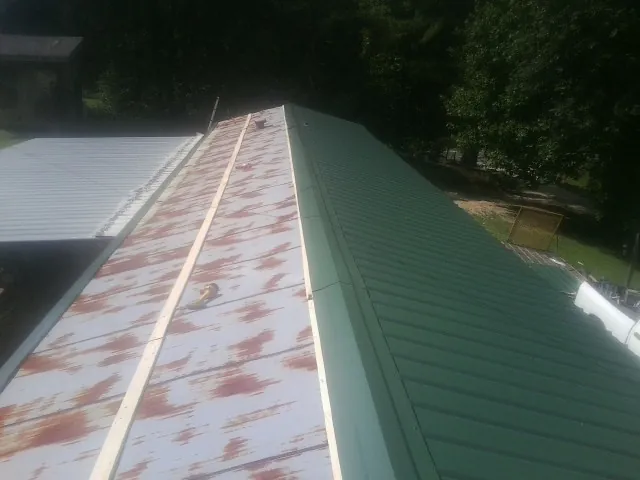 Old rusted panels beside newly installed green metal roofing — Wind Damage Roof Repair by Roofing Brothers in San Gregorio