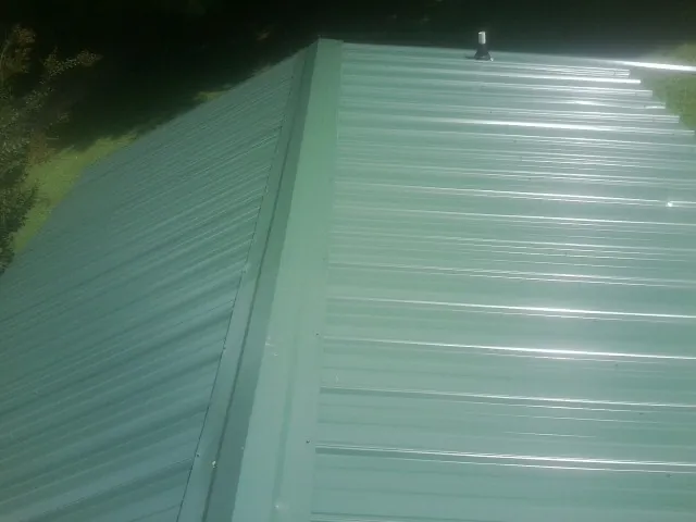 New green metal panels meeting at the ridge of a roof — Flat Roof Repair work by our crew in San Gregorio