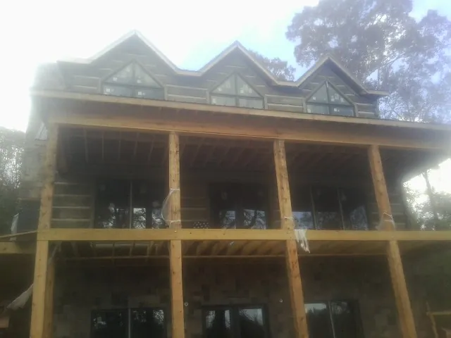 Dormers and porch framing on a large log home under construction — Roof Coating work by our crew in San Gregorio