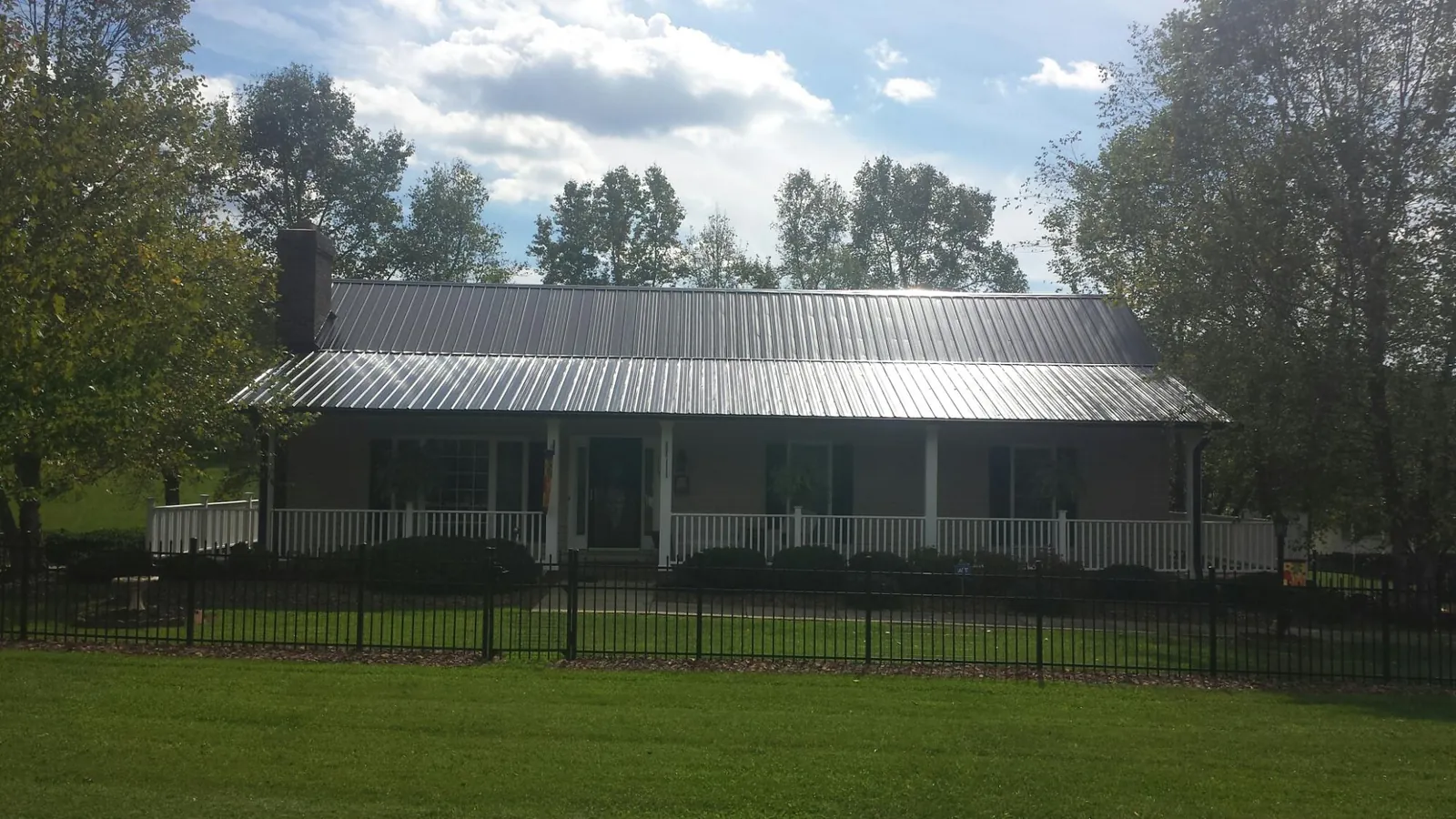 Gray metal roof on a brick ranch with a full width front porch — Gutter Guard Installation work by our crew in San Gregorio