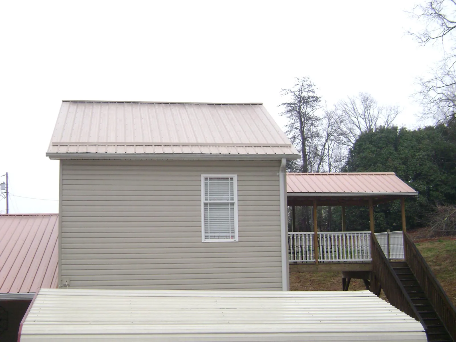 Tan metal roofs on a two story addition and attached porch, from a Roof Replacement job in San Gregorio