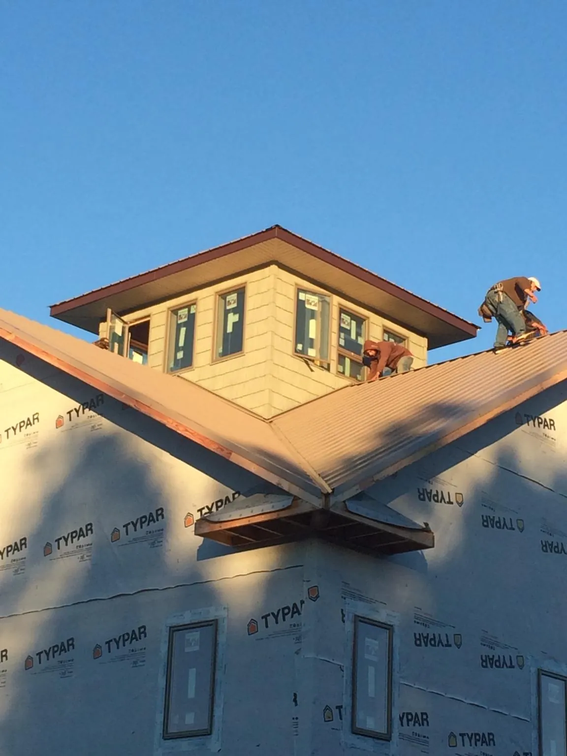 Roofers working around a rooftop cupola on a new metal roof at sunset — Roof Waterproofing in San Gregorio by Roofing Brothers